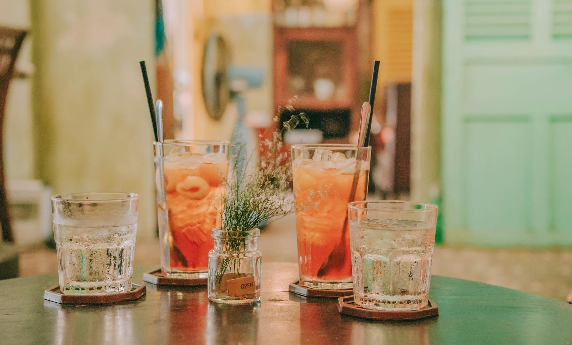 four clear glass drinking cups filled with orange and clear liquids on black surface